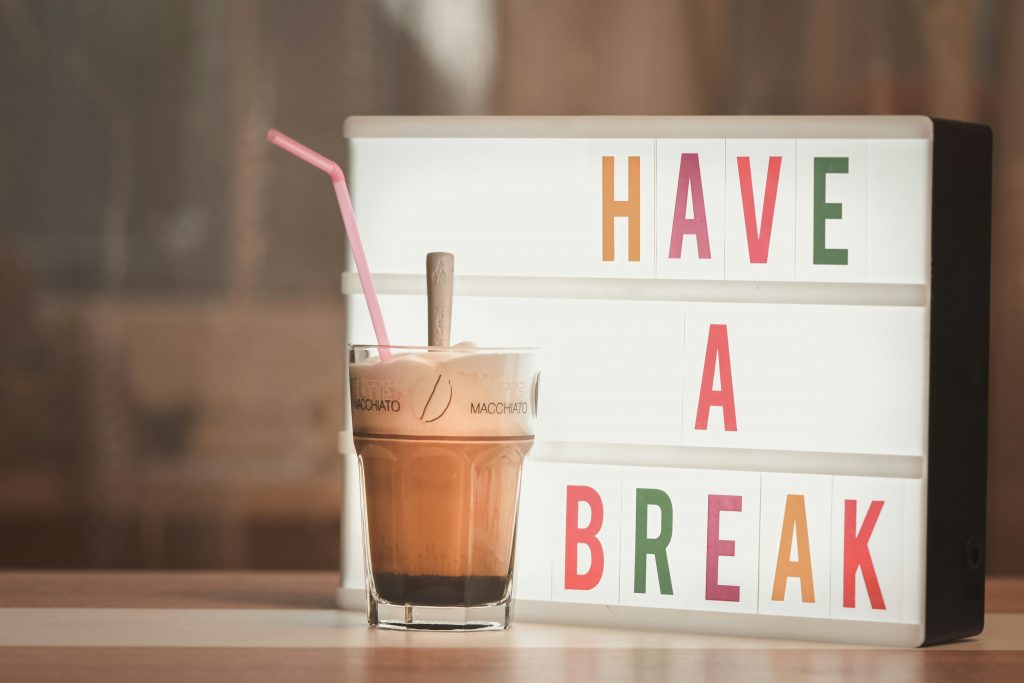 pexels-photo-9773134-9773134 Iced coffee with straw beside illuminated light box saying 'Have a Break'.